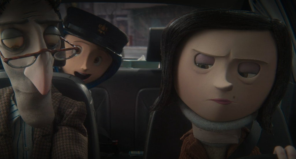 A shot of Coraline's parents from the movie Coraline while they're in the car, with Coraline peeking over her father's shoulder from the backseat.