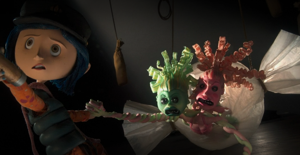 A combined Miss Spink and Miss Forcible in their Other World form crawl out of a large paper candy wrapped chasing Coraline.