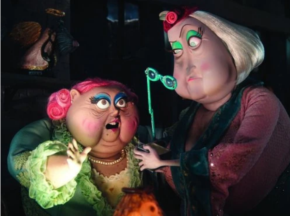 Miss Spink and Miss Forcible from the movie Coraline. Miss Spink is an old, round woman with pink curled hair, blue eyeshadow, a pearl necklace, and a green robe with feathers at the collar and arms. Miss Forcible is an old woman with round cheeks that droop towards her chin, a pink headband, teal eye shadow, a red faded robe with dark blue-green velvet at the collar and cuffs, and she's holding a blue-green pair of spectacles on a stick.